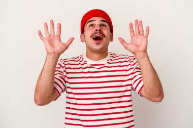 Beyaz arka planda izole edilmiş genç beyaz adam gökyüzüne haykırıyor, yukarı bakıyor, hayal kırıklığına uğramış..