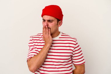 Beyaz arka planda izole edilmiş genç beyaz adam esniyor. Ağzı eliyle kapatan yorgun bir hareket sergiliyor..