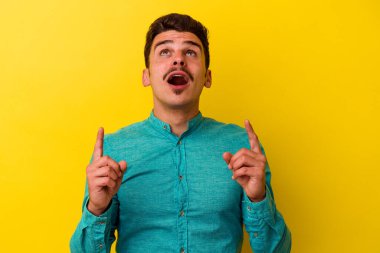 Sarı arka planda izole edilmiş beyaz bir adam ağzı açık bir şekilde üst tarafı işaret ediyor..