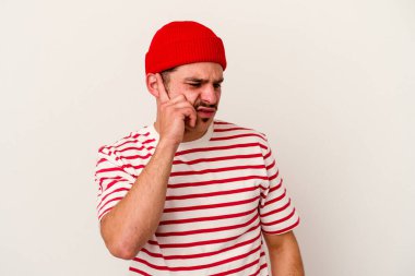 Beyaz arka planda izole edilmiş genç beyaz bir adam kulaklarını elleriyle kapatıyor..