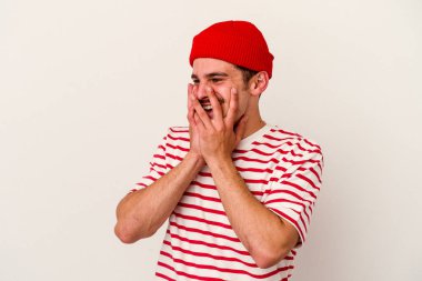 Beyaz arka planda izole olmuş genç beyaz bir adam bir şeye gülüyor, ağızlarını ellerle kapatıyor..