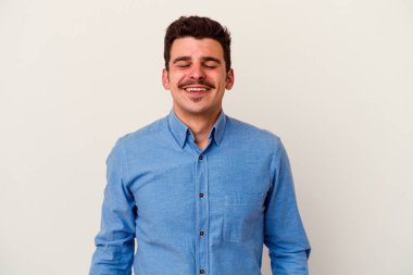 Beyaz arka planda izole edilmiş genç beyaz adam gülüyor ve gözlerini kapıyor, rahatlamış ve mutlu hissediyor..