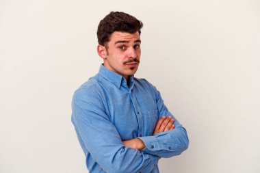 Beyaz arka planda izole edilmiş genç beyaz adam alaycı bir ifadeyle kameraya bakıyor..