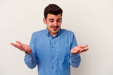 Beyaz arka planda izole edilmiş genç beyaz bir adam elinde avuç içi bir şeyle kameraya sunuyor..