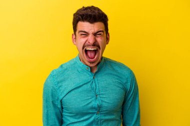 Sarı arka planda izole edilmiş genç beyaz adam çok sinirli ve agresif çığlıklar atıyor..