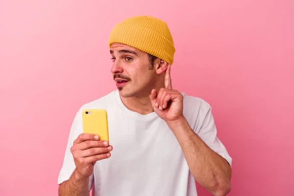 Młody Biały Człowiek Trzymając Telefon Komórkowy Odizolowany Różowym Tle Próbuje — Zdjęcie stockowe