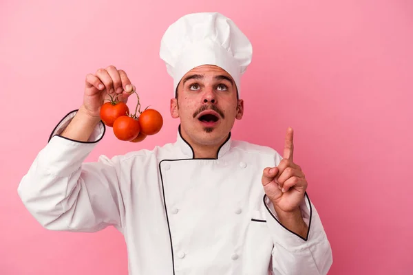 Young Caucasian Chef Man Holding Tomatoes Isolated Pink Background Pointing — Stock Photo, Image