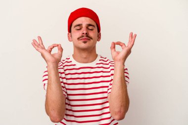 Beyaz arka planda izole edilmiş genç beyaz adam yoğun bir günün ardından rahatlıyor. Yoga yapıyor..