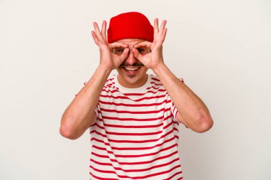 Beyaz arka planda izole genç beyaz adam heyecanlı tamam göz jesti tutmak.