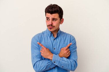 Beyaz arka plan noktalarında izole genç beyaz adam, iki seçenek arasında seçim yapmaya çalışıyor.