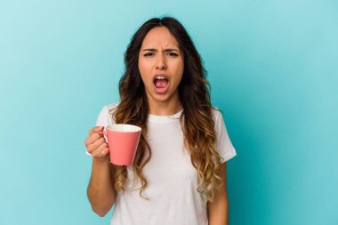 Mavi arka planda elinde kupa tutan genç Meksikalı kadın çok sinirli ve agresif çığlıklar atıyor..
