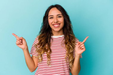 Mavi arka planda izole edilmiş genç Meksikalı kadın farklı fotokopi alanlarını gösteriyor, birini seçiyor, parmaklarıyla gösteriyor..