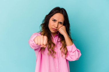 Mavi arka planda izole edilmiş genç Meksikalı kadın bir tartışma yüzünden yumruk, öfke ve kavga atıyor..