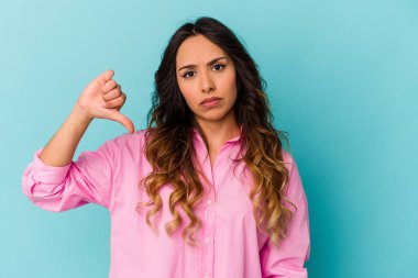 Mavi arka planda izole edilmiş genç Meksikalı kadın hoşlanmadığı bir hareket gösteriyor. Anlaşmazlık konsepti.