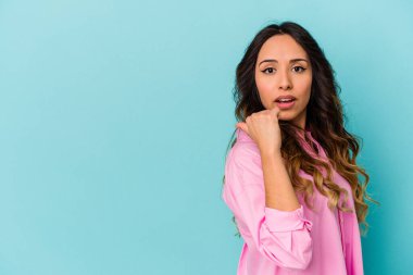 Genç Meksikalı kadın mavi arka planda izole edilmiş başparmak uzakta, gülüyor ve kaygısız.