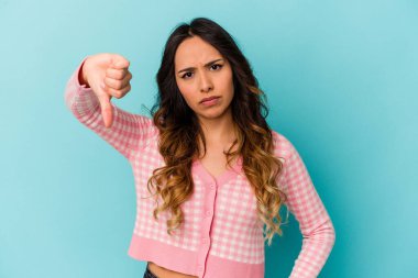Mavi arka planda izole edilmiş genç Meksikalı kadın baş parmağını aşağı gösteriyor, hayal kırıklığı konsepti.