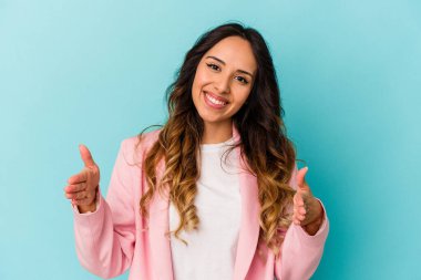 Mavi arka planda izole edilmiş genç Meksikalı kadın iki eliyle bir şey tutuyor, ürün sunumu..