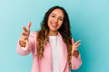 Mavi arka planda izole edilmiş genç Meksikalı kadın kameraya sarıldığı için kendinden emin..