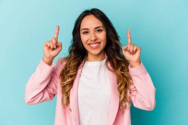 Mavi arka planda izole edilmiş genç Meksikalı kadın iki parmağı da boş bir alan gösteriyor..