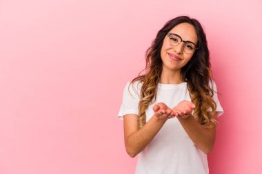 Pembe arka planda izole edilmiş genç Meksikalı kadın dudaklarını katlıyor ve hava öpücüğü göndermek için avuç içleri tutuyor..