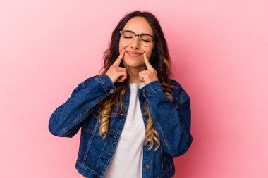 Pembe arka planda izole edilmiş genç Meksikalı kadın iki seçenek arasında şüphe duyuyor.