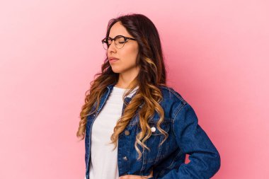 Pembe arka planda izole edilmiş, sırt ağrısı çeken genç Meksikalı kadın..