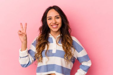 Pembe arka planda izole edilmiş genç Meksikalı kadın iki numarayı parmaklarıyla gösteriyor..