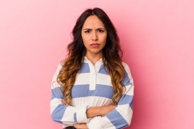 Pembe arka planda izole edilmiş genç Meksikalı kadın yanakları patlatıyor, yorgun bir ifadesi var. Yüz ifadesi kavramı.