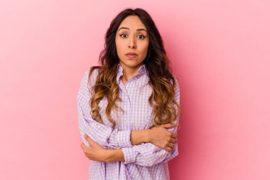 Pembe arka planda izole edilmiş genç Meksikalı kadın omuz silkiyor ve gözleri açık..