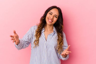 Pembe arka planda izole edilmiş genç Meksikalı kadın hoş bir ifade sergiliyor..