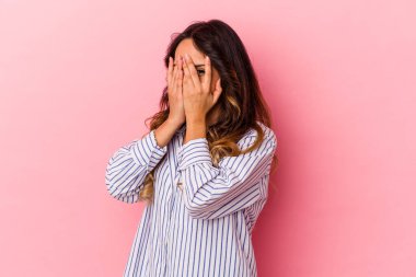 Pembe arka planda izole edilmiş genç Meksikalı kadın parmaklarıyla gözünü kırp korkmuş ve gergin..