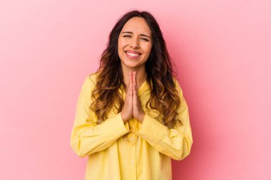 Pembe arka planda izole edilmiş genç Meksikalı bir kadın. El ele tutuşup dua ediyor. Kendine güveniyor..