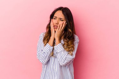 Genç Meksikalı kadın pembe arka planda izole edilmiş sızlanıyor ve ağlıyordu..