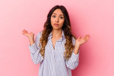 Pembe arka planda izole edilmiş genç Meksikalı kadın sorgulama sırasında omuz silkiyor ve şüphe duyuyor..