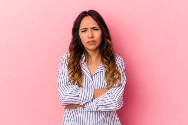 Pembe arka planda izole edilmiş genç Meksikalı kadın şüpheli, belirsiz, seni muayene ediyor..