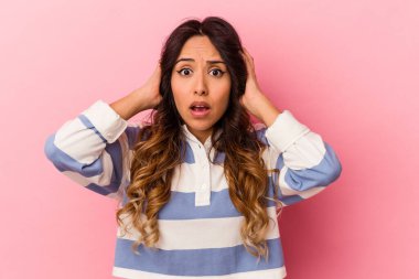 Pembe arka planda izole edilmiş genç Meksikalı kadın kulaklarını elleriyle kapatıyor ve çok fazla ses duymamaya çalışıyor..