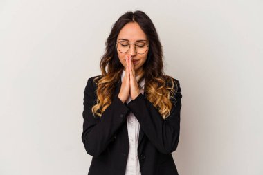 Beyaz arka planda izole edilmiş genç Meksikalı iş kadını el ele dua ederken, kendine güveniyor..