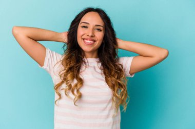 Mavi arka planda izole edilmiş genç Meksikalı kadın kollarını uzatıyor, rahat pozisyonda..