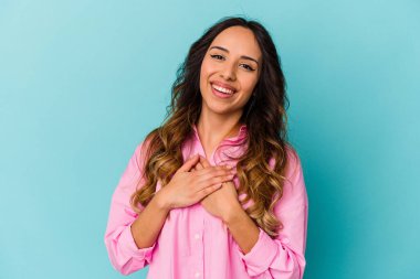 Mavi arka planda izole edilmiş genç Meksikalı kadın avuçlarını göğsüne bastıran dostça bir ifadeye sahip. Aşk konsepti.