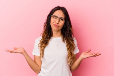 Pembe arka planda izole edilmiş genç Meksikalı kadın sorgulama sırasında omuz silkiyor ve şüphe duyuyor..