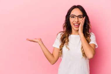 Pembe arka planda izole edilmiş genç Meksikalı kadın avuç içinde fotokopi alanı tutuyor, el üstünde tutuyor. Şaşırmış ve mutlu..