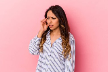 Pembe arka planda izole edilmiş genç Meksikalı kadın kulaklarını elleriyle kapatıyor..