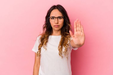 Pembe arka planda izole edilmiş genç Meksikalı kadın elini uzatmış, dur işareti göstererek seni engelliyor..
