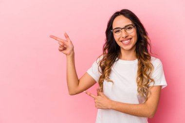 Pembe arka planda izole edilmiş genç Meksikalı kadın işaret parmaklarıyla fotokopi alanını işaret ederek heyecan ve arzusunu ifade ediyor..
