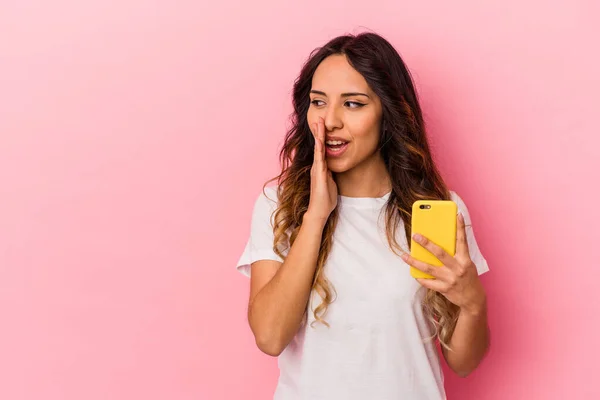 Młoda Meksykanka Trzymająca Telefon Komórkowy Różowym Tle Mówi Sekretne Gorące — Zdjęcie stockowe