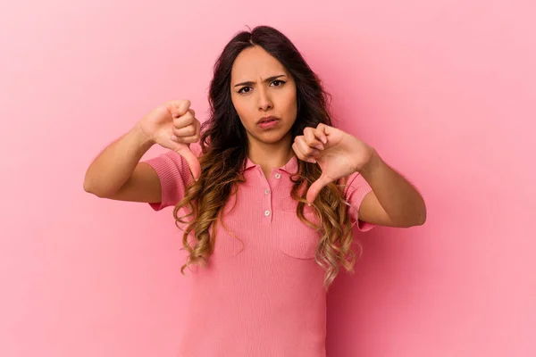 若いメキシコ人女性のピンクの背景に親指を示すと嫌いを表現孤立 — ストック写真