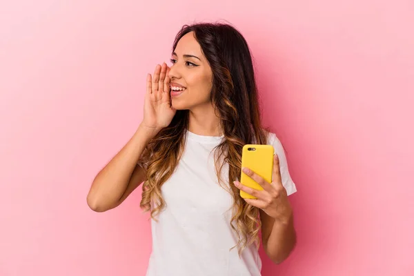 年轻的墨西哥女人拿着一部被粉色背景隔离的手机大喊着 手牵着手掌靠近张开的嘴 — 图库照片