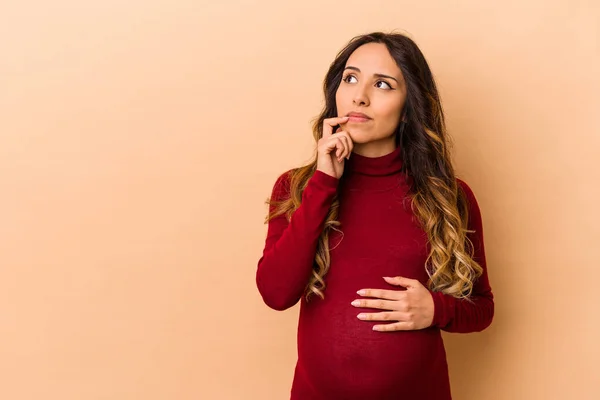 Young Mexican Pregnant Woman Isolated Beige Background Looking Sideways Doubtful — Stock Photo, Image