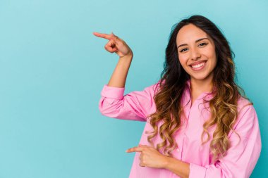 Mavi arka planda izole edilmiş genç Meksikalı kadın işaret parmağıyla işaret ederek heyecanlanıyor..
