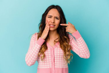Mavi arka planda izole edilmiş genç Meksikalı kadın güçlü bir diş ağrısı ve azı dişi ağrısı var..
